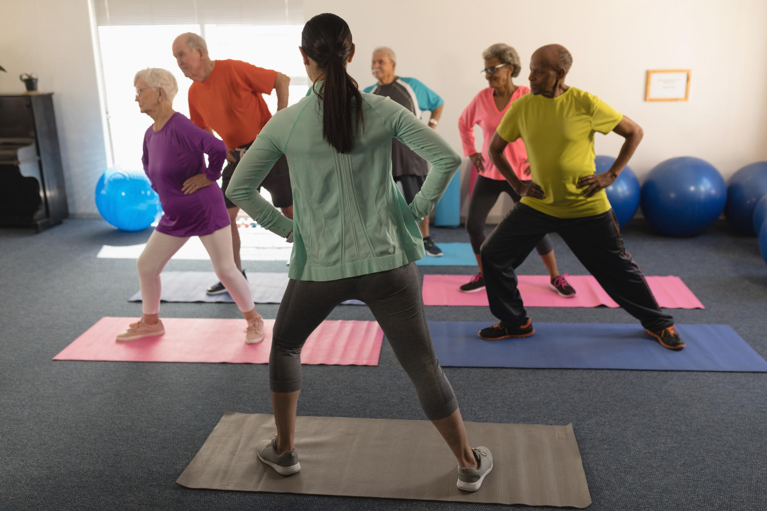 Groepje mensen probeert stress en rugklachten te voorkomen in de oefenzaal door oefeningen uit te voeren zoals pilates.