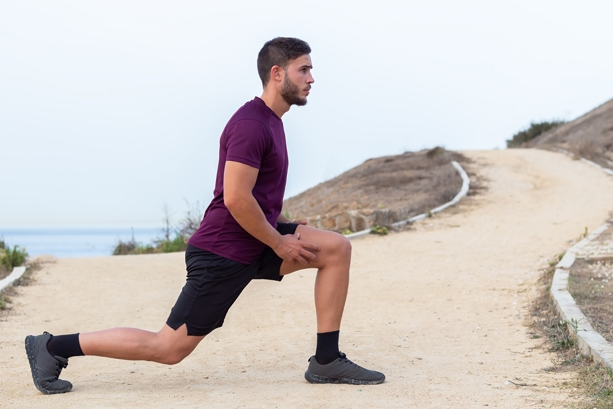 Man met een rood shirt werkt aan Sterke benen op het strand
