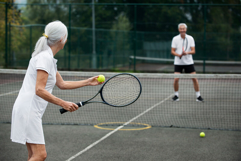 Twee personen zijn aan het tennissen en voorkomen zo een tennisarm